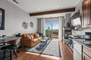 Eine moderne Küche mit Einbauofen, ein Essbereich mit Tisch und Stühlen sowie ein Wohnzimmer mit Sofa und Couchtisch.