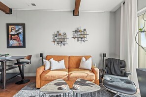 A modern living room with a sofa, coffee table, and chairs. There are abstract wall art pieces and a framed picture on the wall. - Newpark Terrace Retreat - Private Hot Tub + Nature Views • Walk to Shuttle (Park City)