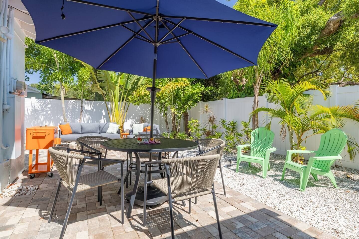 An outdoor patio with a round table, chairs, and a large umbrella.