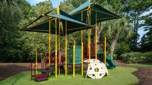 Un parque infantil con estructuras para escalar, toboganes y una zona cubierta.