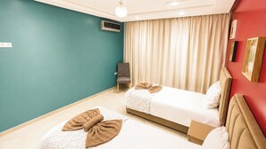 Ein Hotelzimmer mit zwei Betten, einem grauen Sessel, einer Deckenleuchte und einer Wand-Klimaanlage.