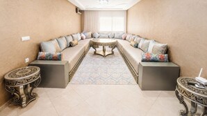 Ein modernes Wohnzimmer mit einer gebogenen Couch, einem gemusterten Teppich und dekorativen Beistelltischen.