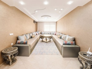 Ein modernes Wohnzimmer mit einer gebogenen Couch, einem gemusterten Teppich und dekorativen Beistelltischen.