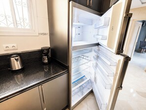 Eine moderne Küche mit einem Edelstahl-Kühlschrank, einer Kaffeemaschine und einem Wasserkocher auf der Arbeitsplatte.