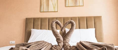A hotel room with a bed, two pillows, and a wall with two framed pictures.