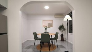 En matplats med ett runt bord, fyra stolar, en krukväxt och en golvlampa.