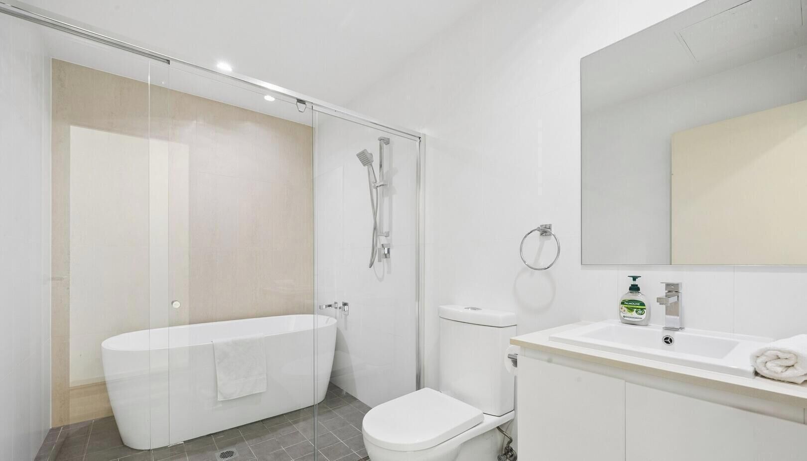 Un baño moderno con ducha envuelta en vidrio, una bañera independiente y un inodoro.