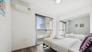 Habitación de hotel con cama, baño y puerta corrediza de vidrio que da a un espacio exterior.