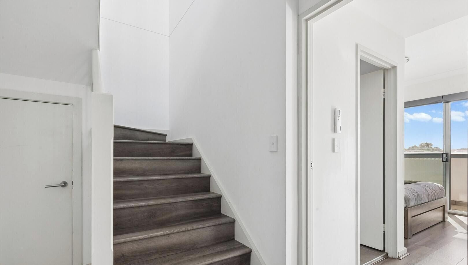 A staircase leading to a balcony with a bed.