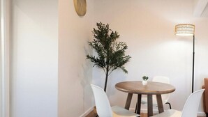 En matplats med ett runt bord, två vita stolar, en liten krukväxt och en golvlampa.