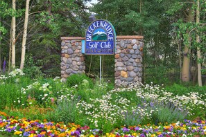 A sign for a golf club with a stone archway, surrounded by a variety of flowers. - NEW Double Eagle Lodge on Golf Course, Hot Tub, Gym, VIEWS Outdoor Paradise (Breckenridge)