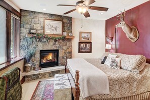 A bedroom with a stone fireplace, a ceiling fan, a mounted deer head, and a bed with patterned bedding. - NEW Double Eagle Lodge on Golf Course, Hot Tub, Gym, VIEWS Outdoor Paradise (Breckenridge)