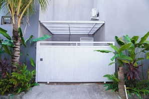 A gated entrance with a white gate, a grey wall, and various tropical plants. - Private 2BR Villa & Pool - Rice Field Views - Canggu (Dalung)