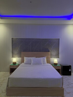A modern hotel room with a large bed, two bedside tables with lamps, a marble-patterned headboard, and a ceiling with blue LED lighting. - Private 2BR Villa & Pool - Rice Field Views - Canggu (Dalung)