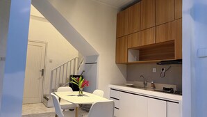 A modern kitchen with white cabinetry, a dining table with chairs, and a staircase leading to another level. - Private 2BR Villa & Pool - Rice Field Views - Canggu (Dalung)