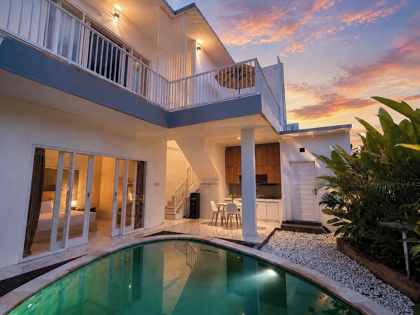 A two-story house with a swimming pool, a balcony, and a kitchen area.