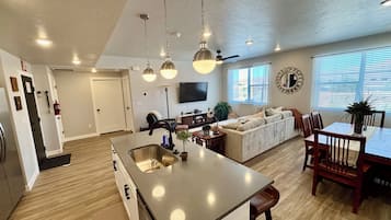 A spacious living area with a large island, a sofa, and a dining table.