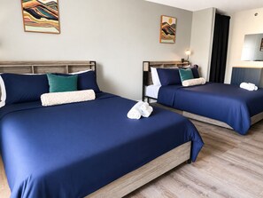 Ein Hotelzimmer mit zwei Betten, jeweils mit dunkelblau bett eingedeckt und Kissen, einem hölzernen Kopfteil und einem Bild an der Wand.
