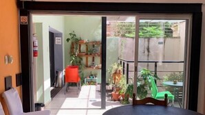A room with a table and chairs, a sliding glass door leading to an outdoor area with plants and a chair. - Go Hostel (Córdoba)