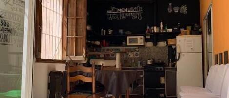 Una cocina compacta con ventilador de techo, un comedor con sillas y una mesa.