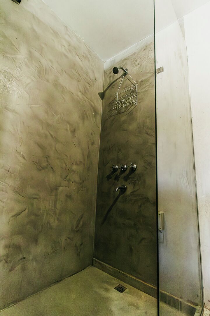 Ducha con mampara de vidrio, cabezal de ducha de mano y grifo empotrado.