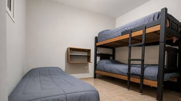 Un dormitorio con literas, una cama individual y un pequeño armario.