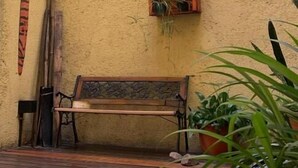 A wooden bench, a small planter with plants, and a wall-mounted shelf with a plant.