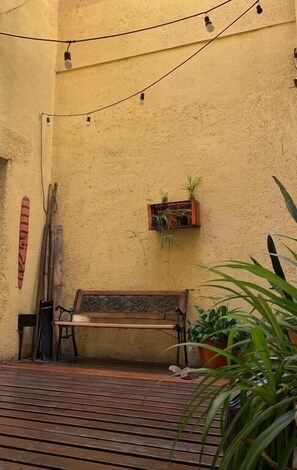 A wooden bench, a small planter with plants, and a wall-mounted shelf with a plant. - Go Hostel (Córdoba)