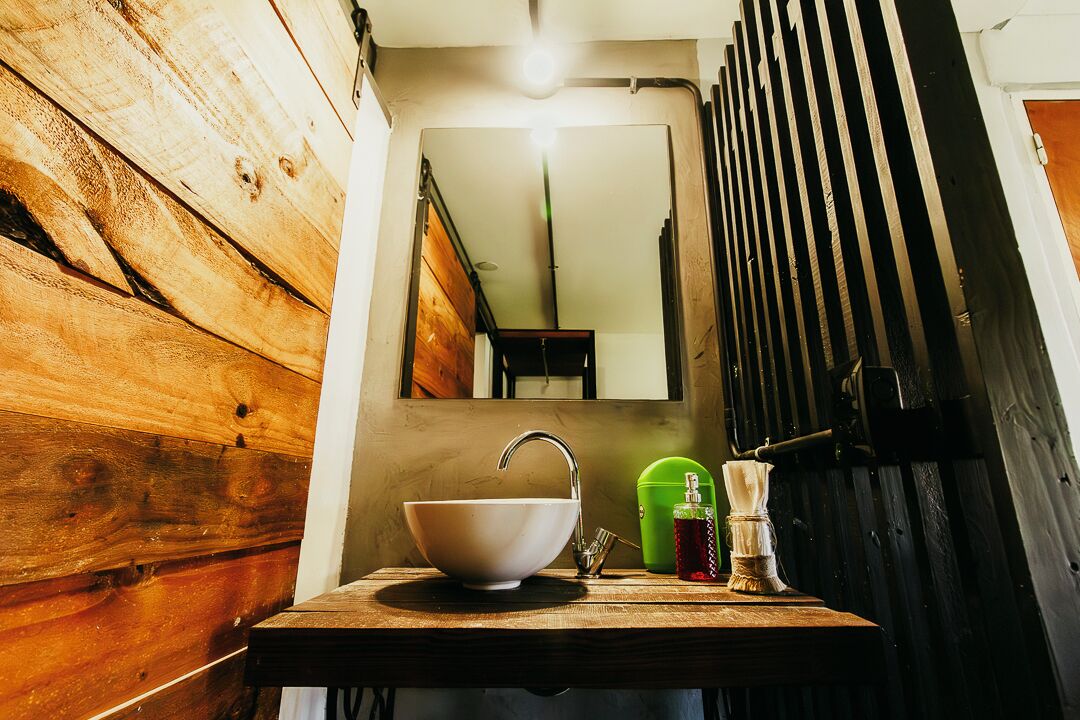 A rustic bathroom with a wooden vanity, a white sink, and a mirror above it.