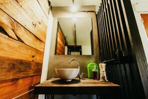 A rustic bathroom with a wooden vanity, a white sink, and a mirror above it.