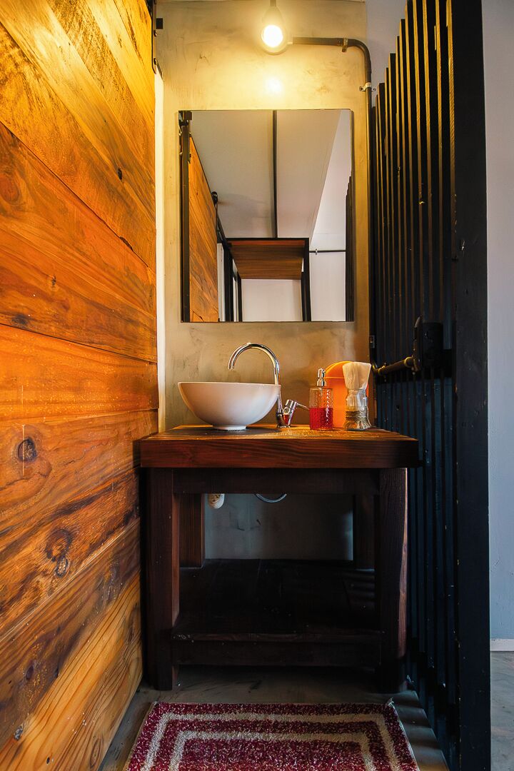 A bathroom with a wooden wall, a sink with a mirror, and a red rug.