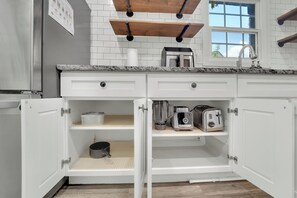 Eine Küche mit weißen Schränken, einer Granit Arbeitsplatte, einer Kaffeemaschine, einem Toaster und einem Mixer.