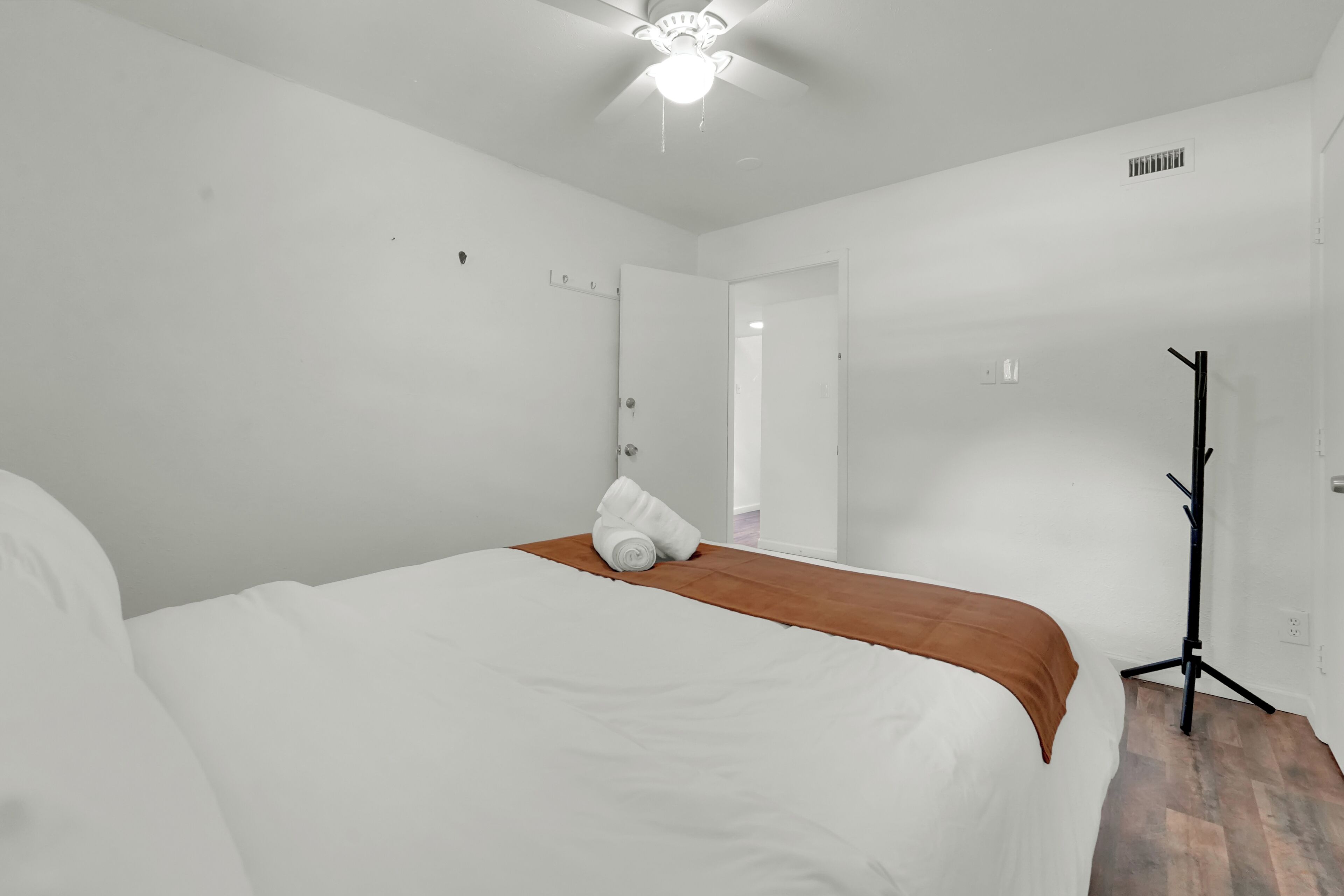 Une chambre d’hôtel avec un lit, un radiateur mobile et une porte donnant sur une autre pièce.