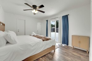 A bedroom with a bed, a ceiling fan, a window with curtains, and a wooden cabinet. - Spacious Entire Home •4BR  •7 Beds •Sleeps 12+ • Near Dallas, Plano, Richardson (Garland)