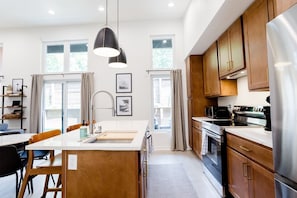 A modern kitchen with wooden cabinets, stainless steel appliances, and a large island with a sink.
