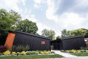 Two modern, black wooden cabins with a number '500' sign, surrounded by well-maintained landscaping and trees.