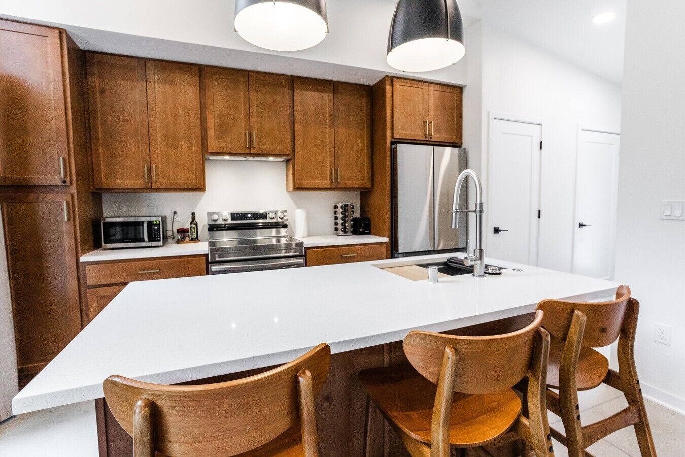Une cuisine moderne avec des meubles en bois, des appareils en acier inoxydable et un îlot central doté de chaises.