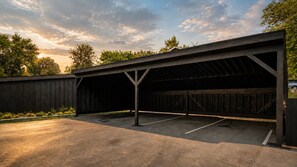 A covered parking area with a concrete floor and metal beams.