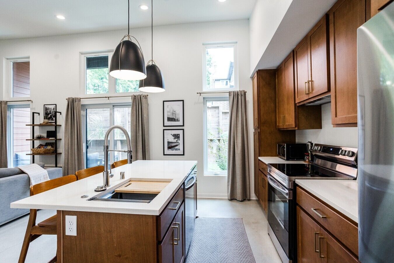 A modern kitchen with wooden cabinets, a central island with a sink, and a built-in oven.