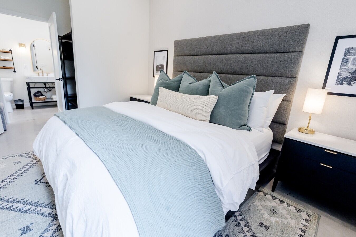 A modern bedroom with a large bed, a bedside table with a lamp, and a headboard.