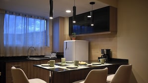 Una cucina moderna con zona pranzo, dotata di frigorifero, macchina del caffè e sgabelli da bar.