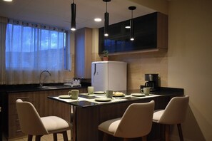 Eine moderne Küche mit Essbereich, inklusive Kühlschrank, Kaffeemaschine und Barhocker.