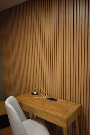 A wooden-paneled wall, a white chair, and a wooden table with a smartphone and earphones on it. - A nice, centrally located apartment in Sopocachi, La Paz. (La Paz)