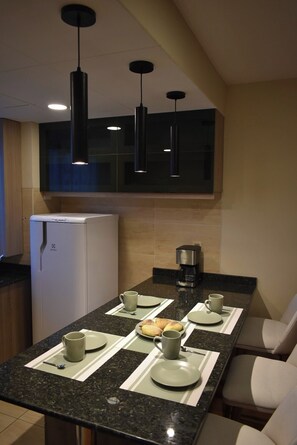 A modern kitchen with a built-in refrigerator, a coffee maker, and a dining area with a table set for two. - A nice, centrally located apartment in Sopocachi, La Paz. (La Paz)