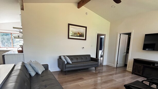 A spacious living room with a grey sofa, a coffee table, and a ceiling fan. - Château Kozy Kove (Kawartha Lakes)