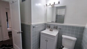 A bathroom with a white sink, a mirror, and a toilet. - Airport-Adjacent 3 Bedroom 2 Bath Cottage (Charlotte)