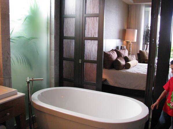 A bathroom with a freestanding bathtub, a mirror, and a sink.