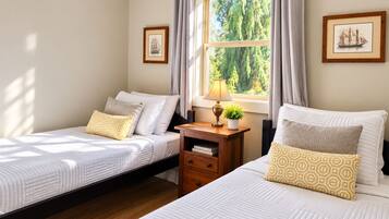 Ein Schlafzimmer mit zwei Betten, einem Nachttisch mit Lampe und gerahmten Bildern an der Wand.