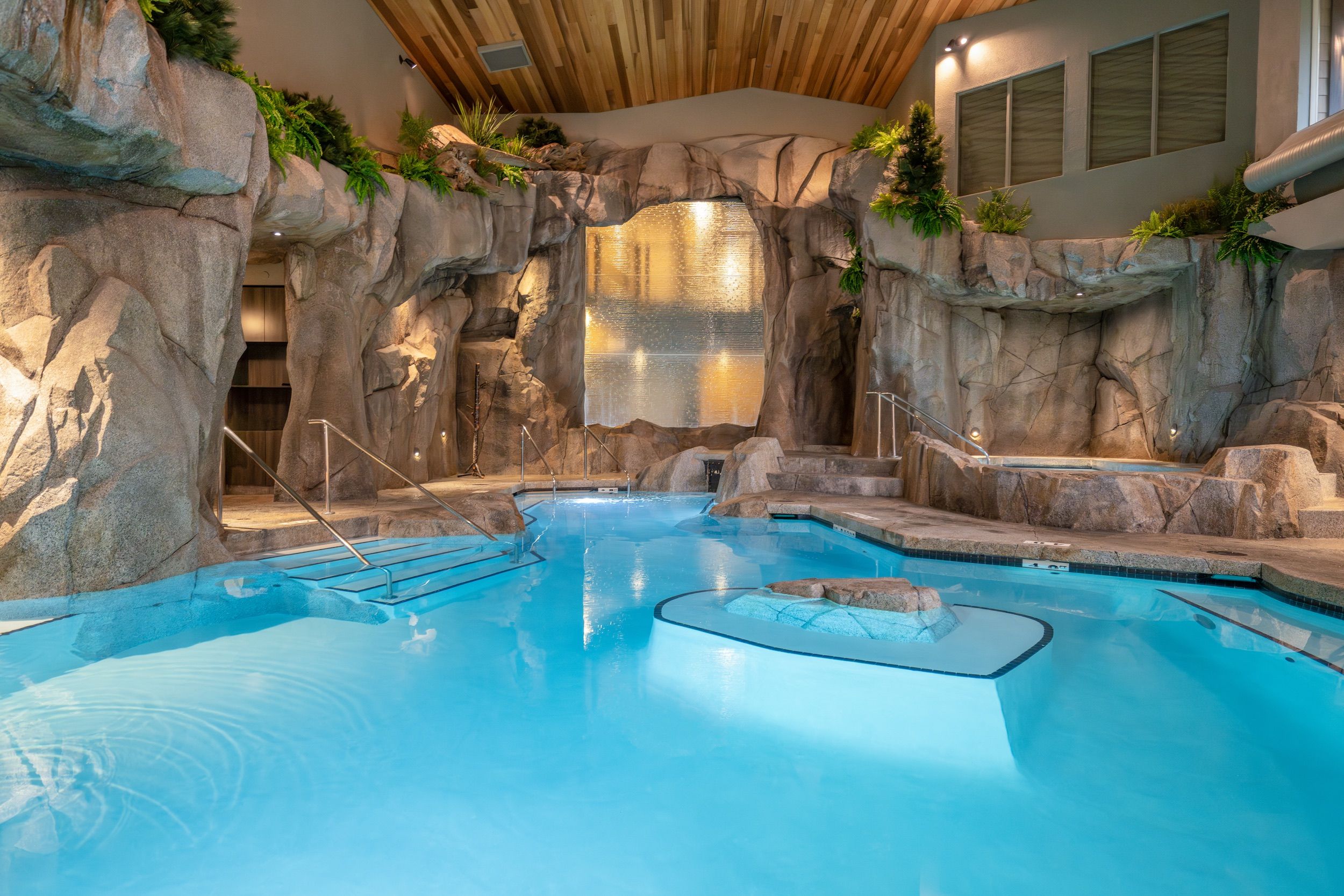 An indoor swimming pool with rock formations and stairs.