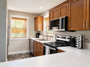 A modern kitchen with wooden cabinets, a stainless steel range, and a microwave.